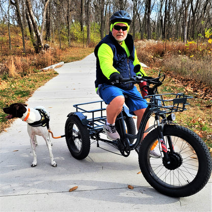 a rider on a black rugged fat tire adult trike with a german shorthaired pointer attached with an orange bike tow leash & Trike adaptor